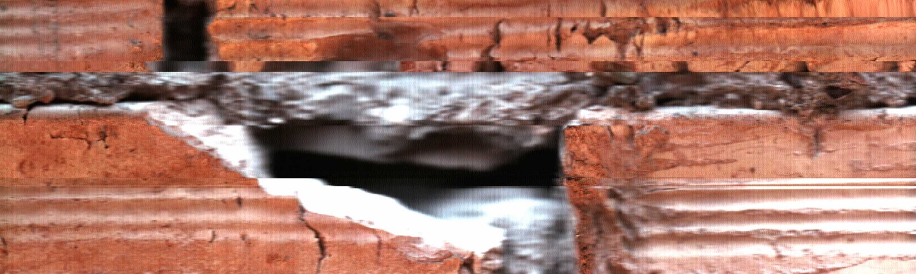 El hueco entre piezas rojizas revela un interior oscuro y bordes irregulares.