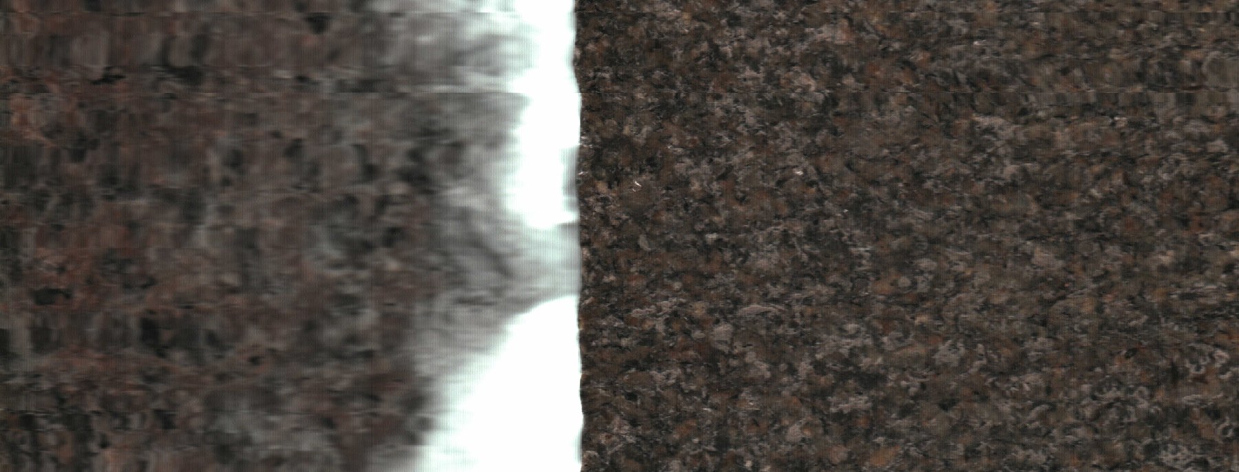 Una franja blanca divide dos zonas de textura oscura y granular.