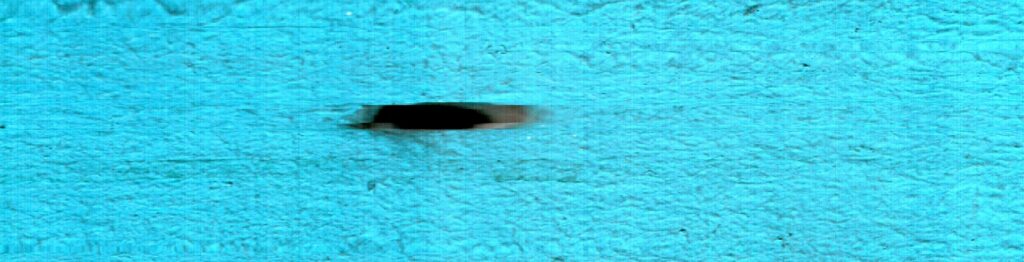 Una pequeña marca oscura concentra la mirada sobre un campo turquesa.