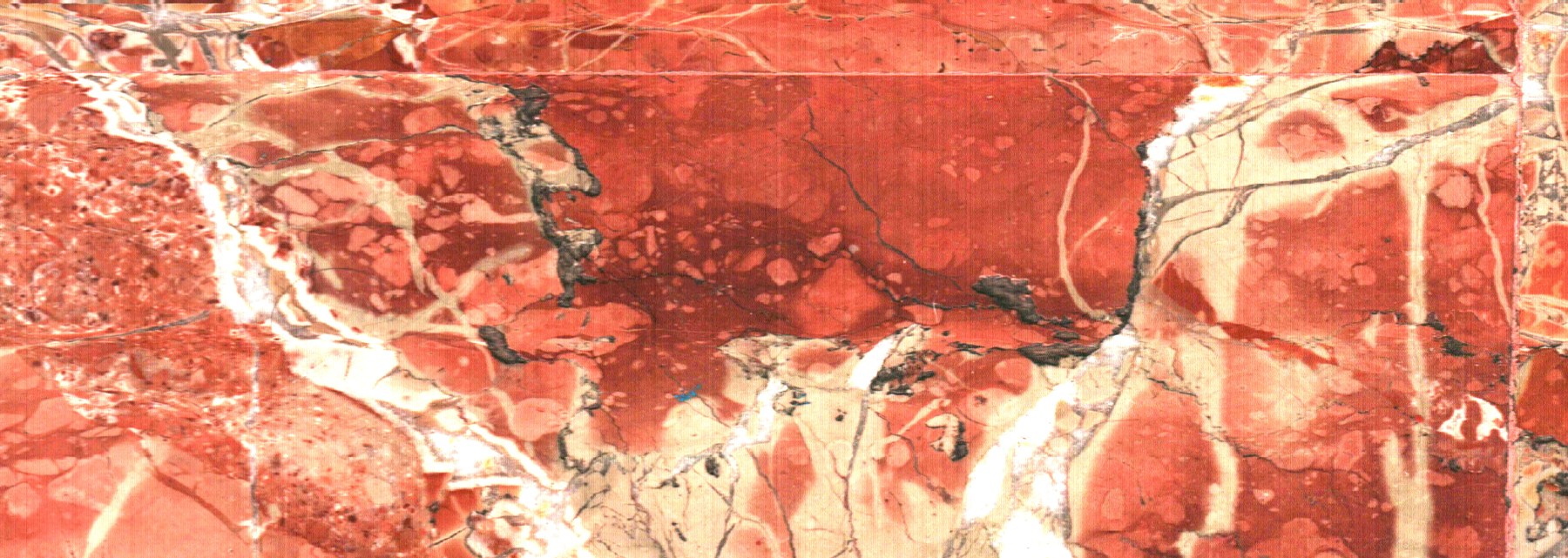 Líneas claras cruzan una superficie roja veteada como un mapa mineral.