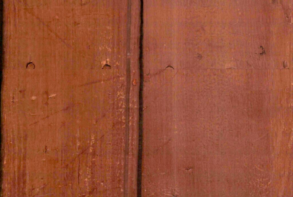 una junta vertical separa dos planos rojizos marcados por vetas, puntos y pequeños roces.